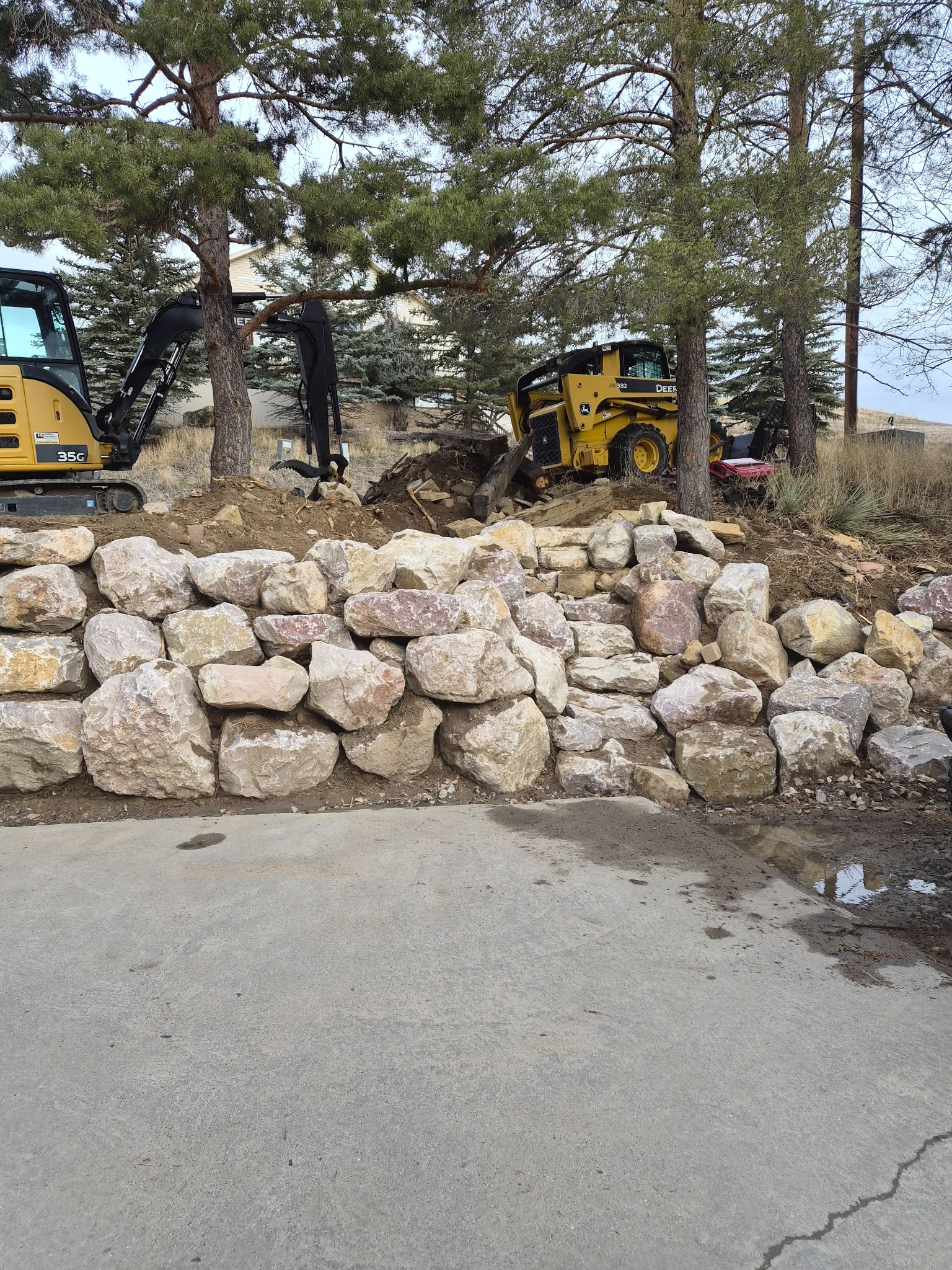 Skid steer and mini excavator doing dirt work and retaining wall support